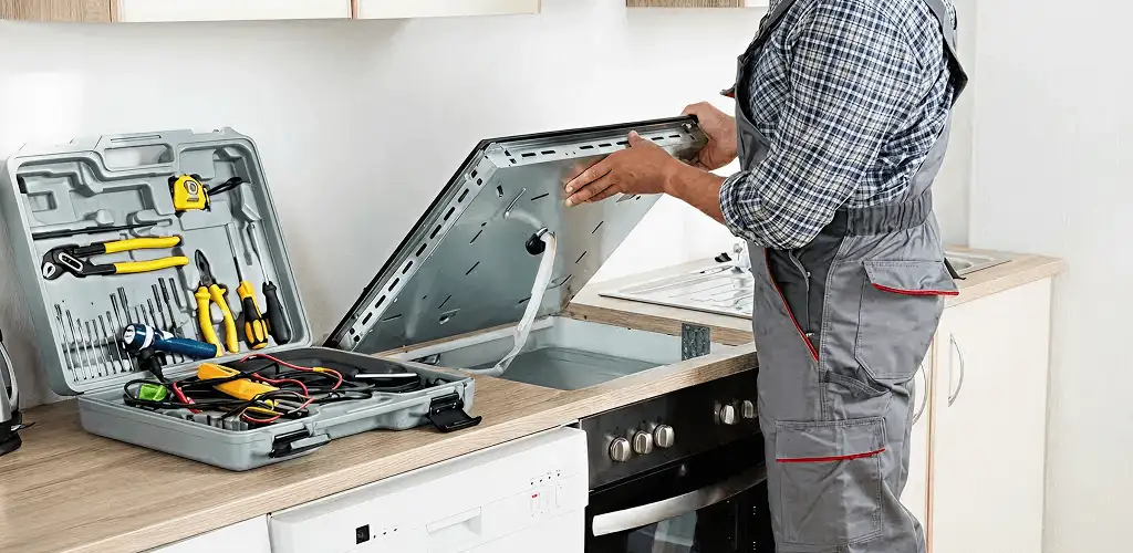 Handyman repairing a cooktop and checking wiring connections in Pembroke Pines, FL
