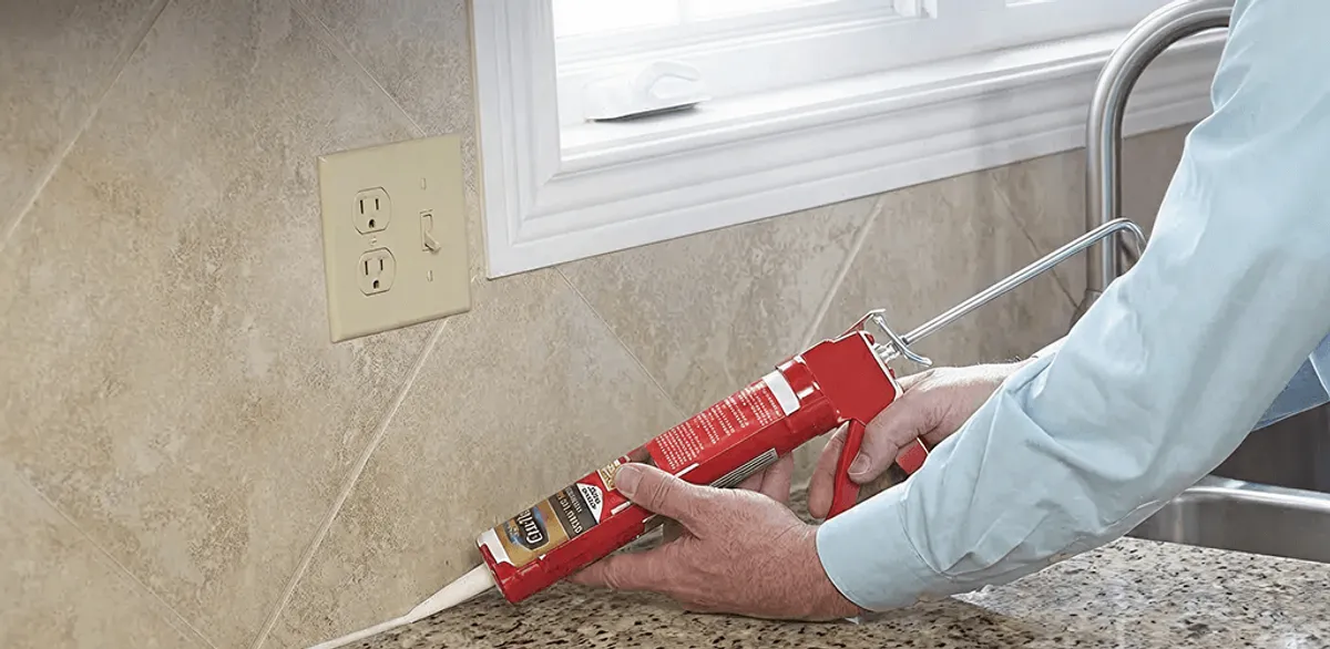 Handyman applying caulk along a kitchen backsplash and countertop seam in Pembroke Pines, FL