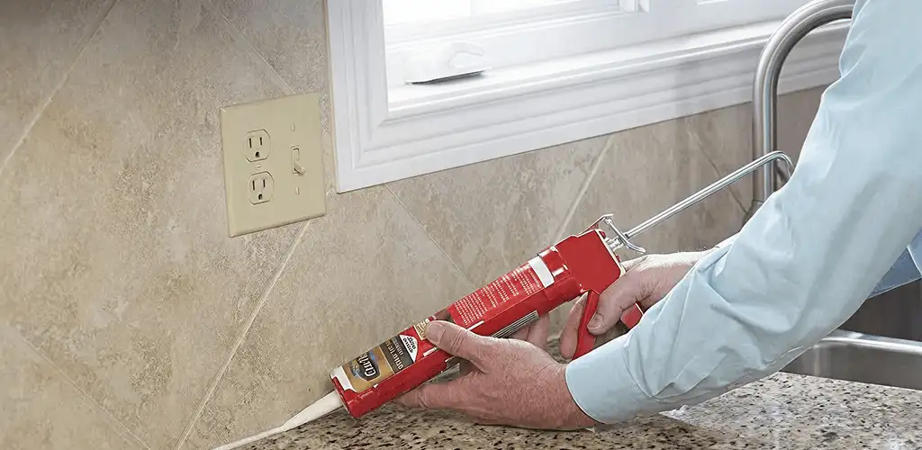 Handyman applying caulk along a kitchen backsplash and countertop seam in Pembroke Pines, FL