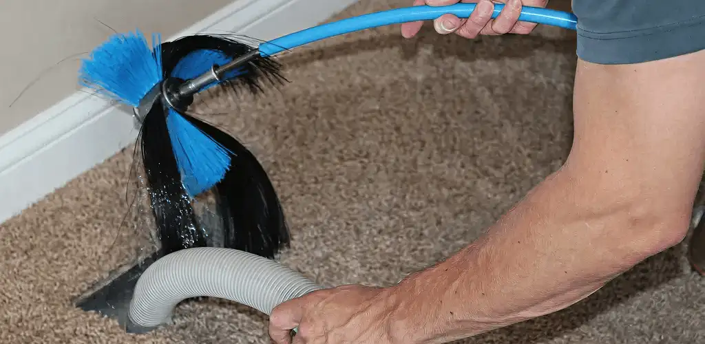 Dryer vent cleaning technician brushing lint from a vent line in Pembroke Pines, FL