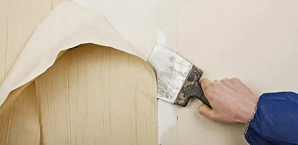 Handyman removing wallpaper with a scraper for wall preparation in Pembroke Pines, FL