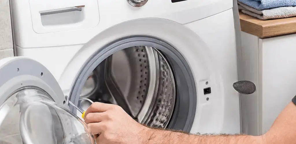 Handyman repairing a front-load washing machine and inspecting the drum in Pembroke Pines, FL
