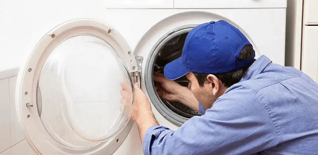 Washing machine repair handyman inspecting a front-load washer drum in Pembroke Pines, FL