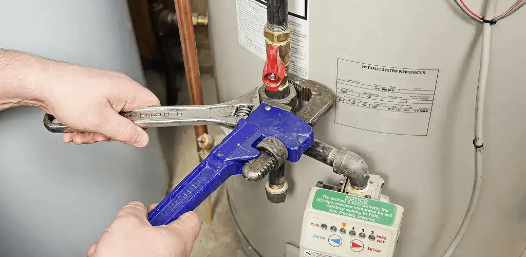 Water heater repair technician tightening the shutoff valve and supply line in Pembroke Pines, FL